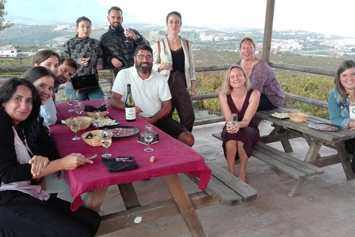 un gruppo di persone sedute attorno a un tavolo con una bottiglia di vino