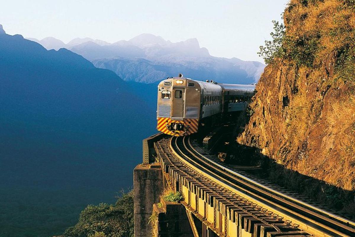 a train on the tracks next to a mountain