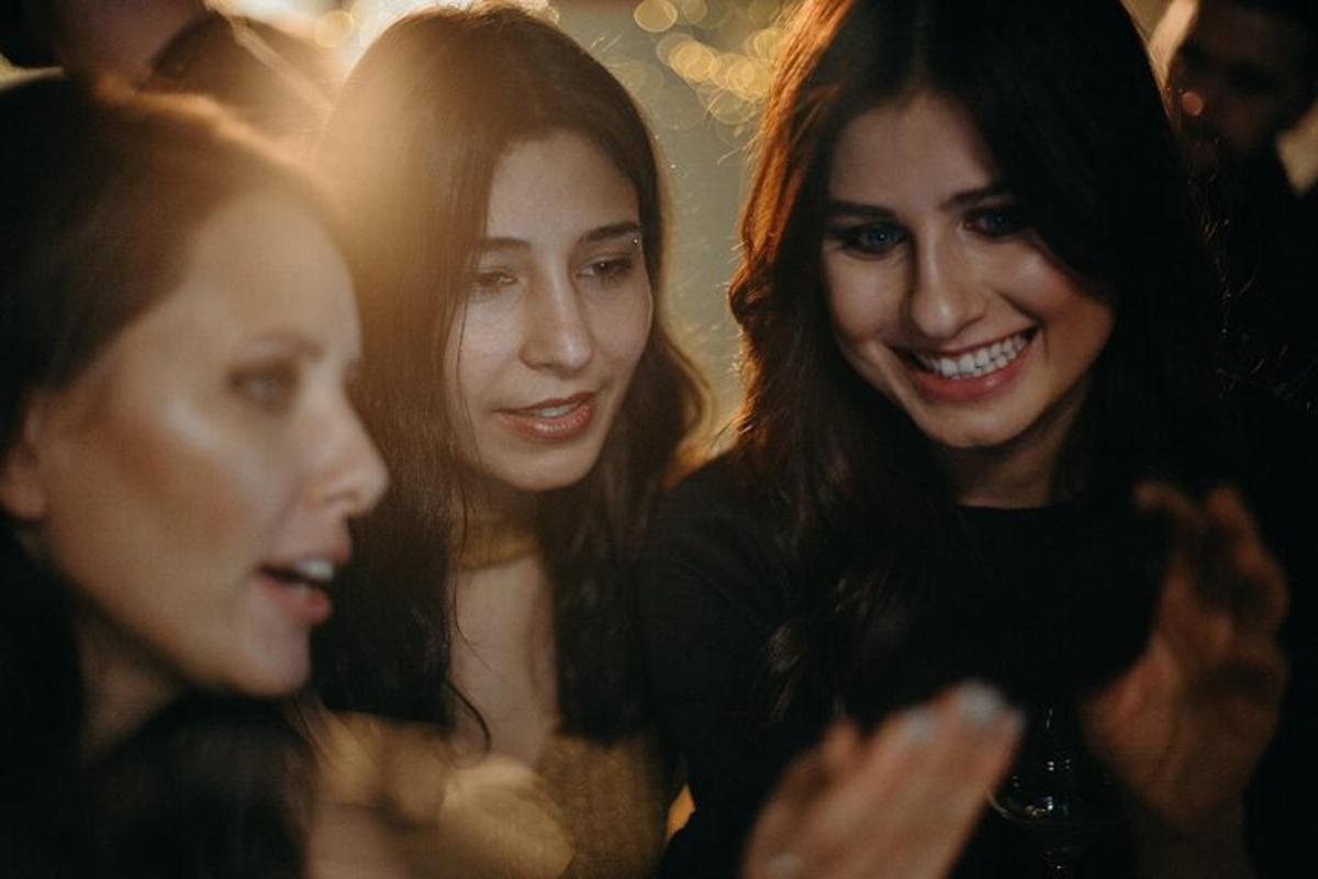um grupo de três mulheres olhando para um celular