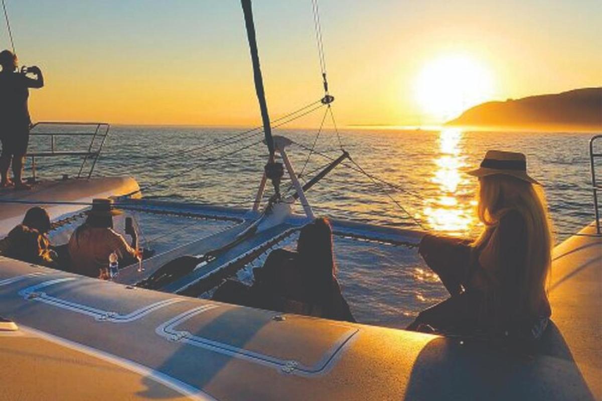 sekelompok orang yang duduk di atas perahu saat matahari terbenam