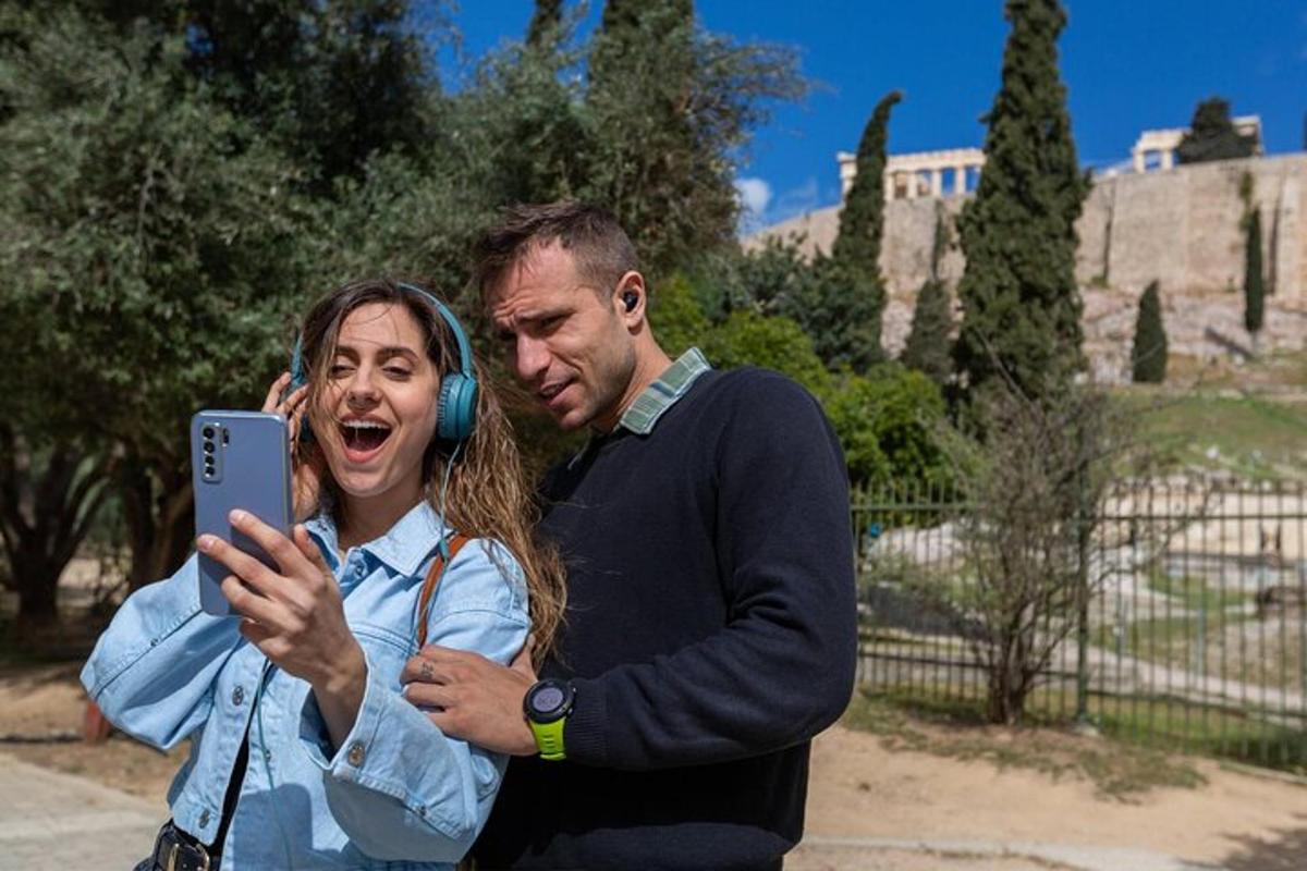 a man and woman wearing headphones taking a picture with a cell phone