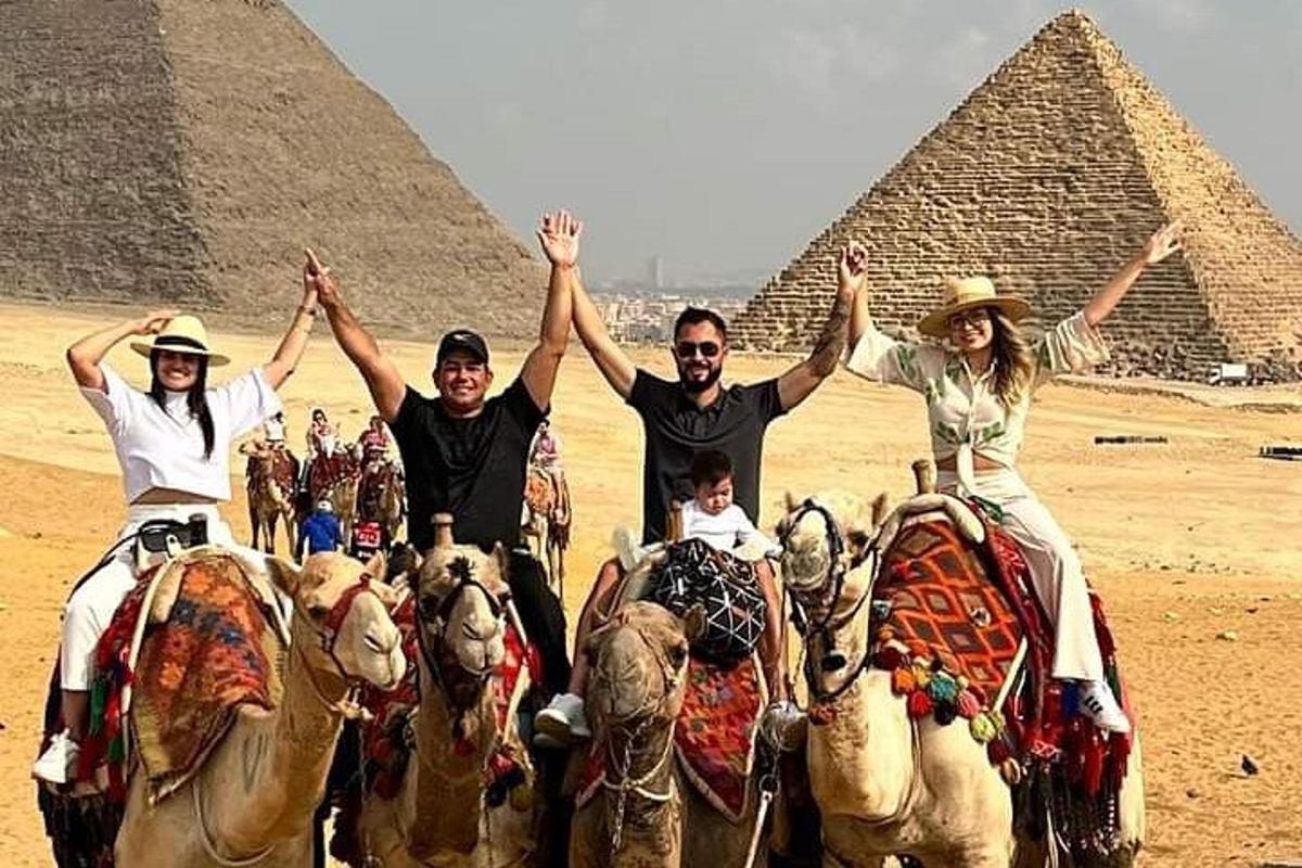 Skupina lidí na koních před pyramidami