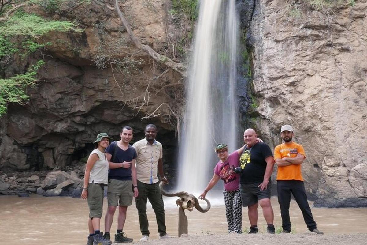 um grupo de pessoas em pé em frente a uma cachoeira