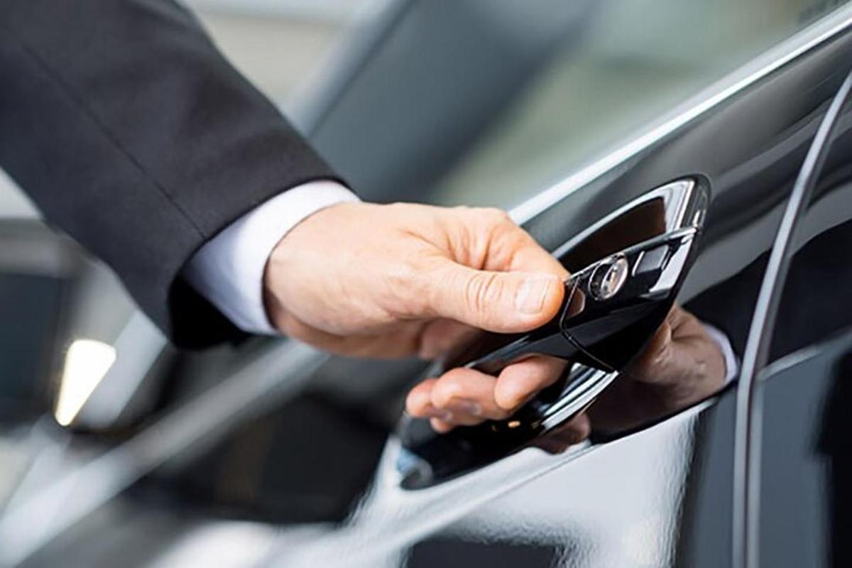a man in a suit holding a cell phone to a car