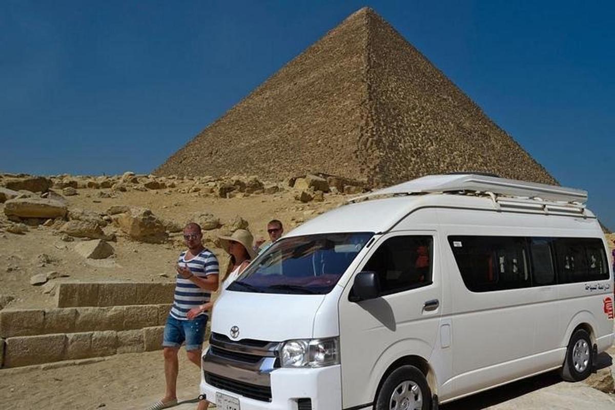skupina lidí stojící vedle dodávky před pyramidou
