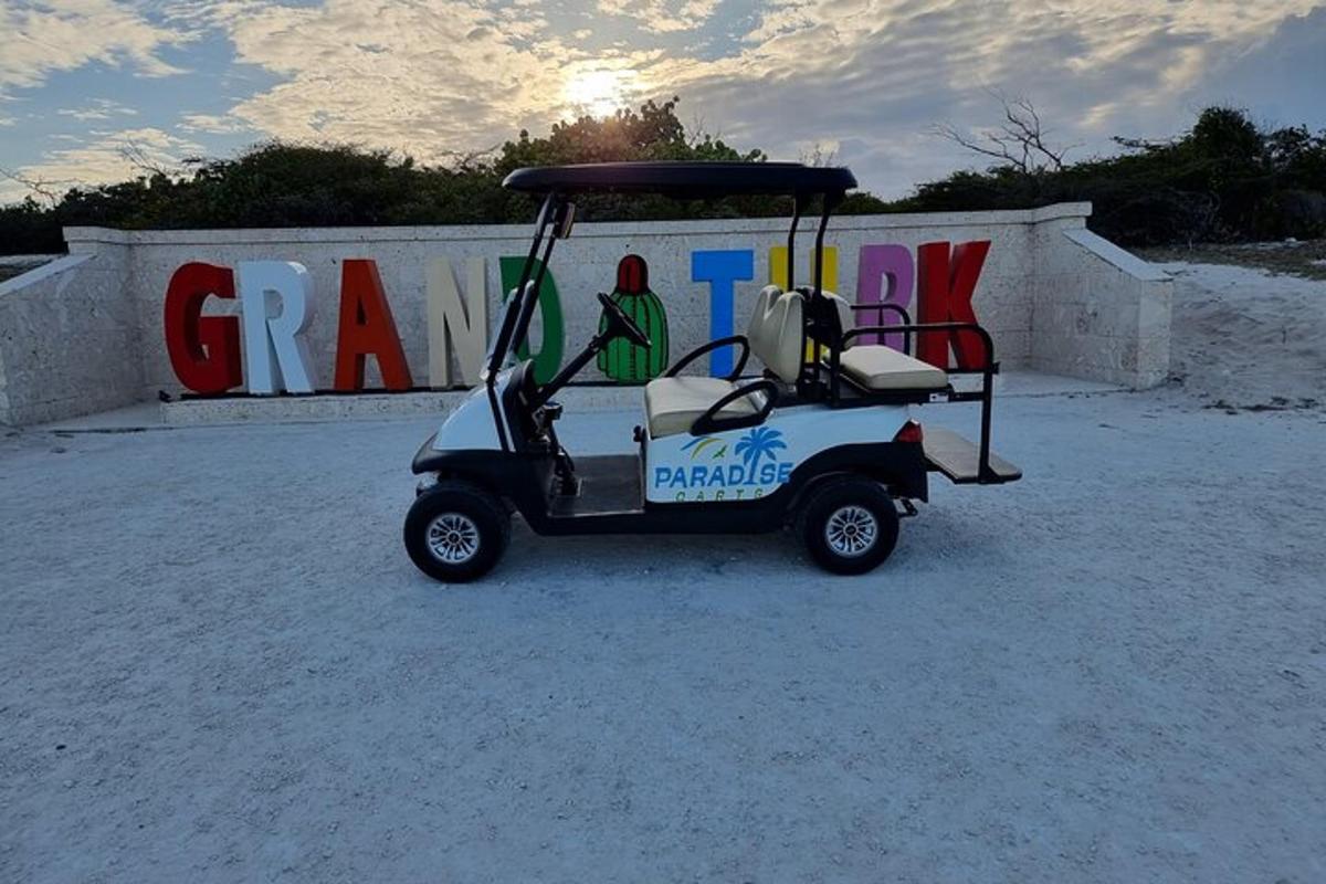 a golf cart parked in the sand in front of a sign