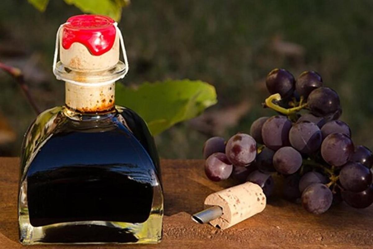 uma garrafa de vinho ao lado de um cacho de uvas