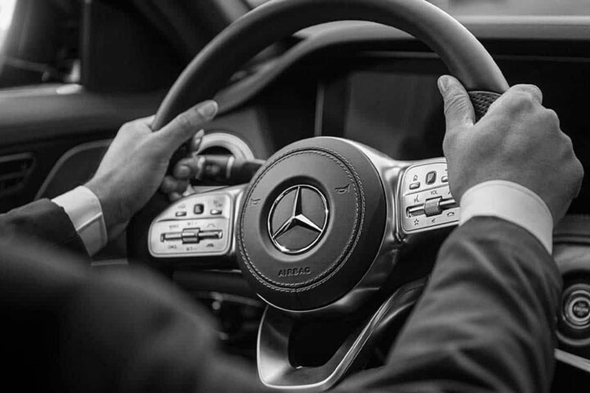 un home conduint un cotxe amb les mans al volant