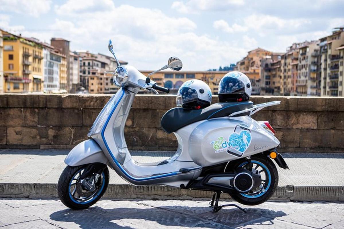 a silver scooter parked on a street with two helmets