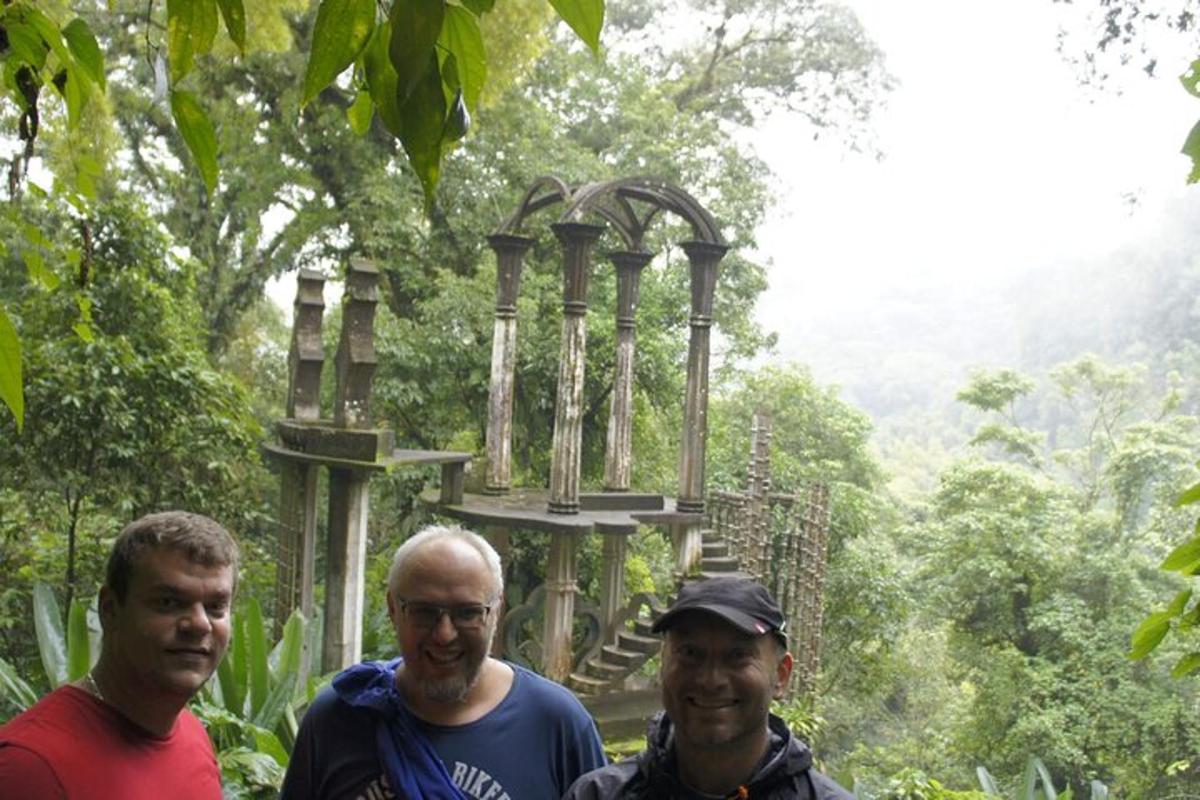 three men standing in front of a structure in the forest