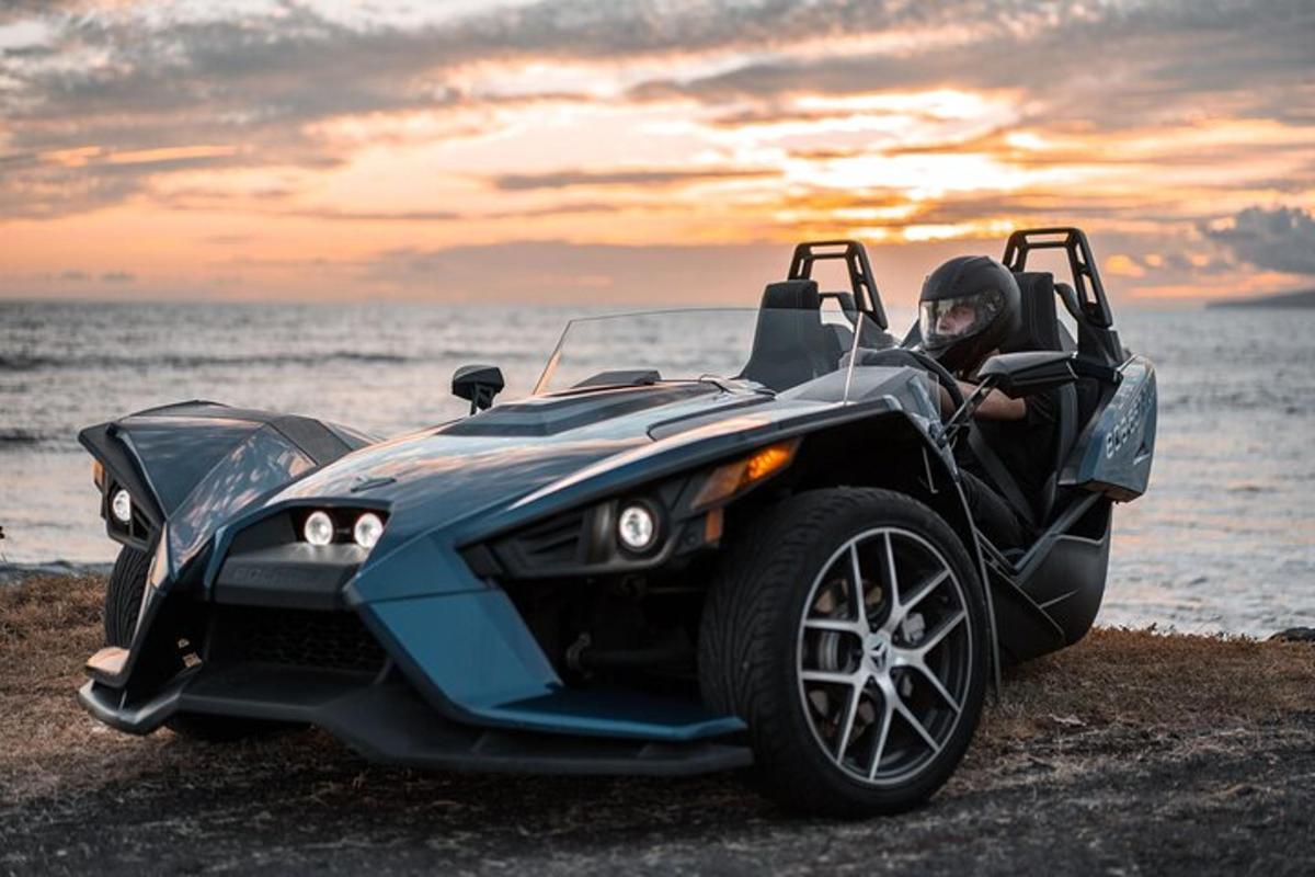 Una mujer está sentada en un coche en la playa.