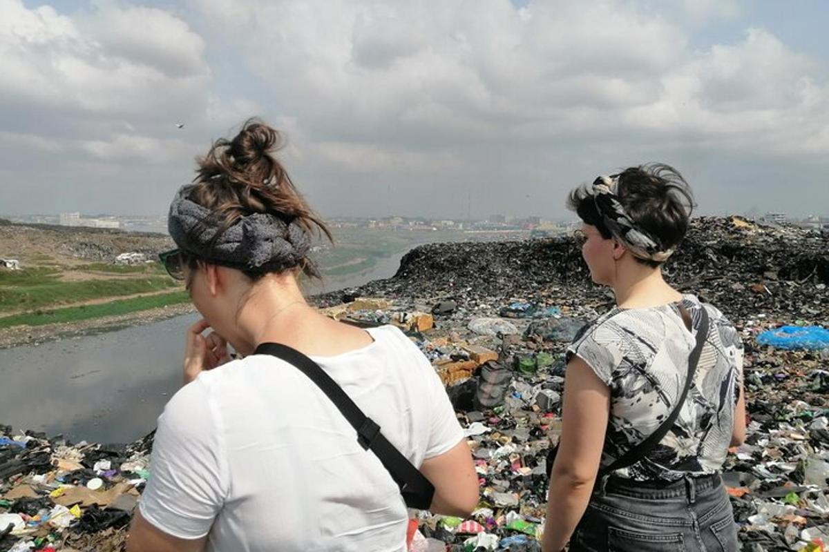 duas mulheres em pé em cima de uma pilha de lixo
