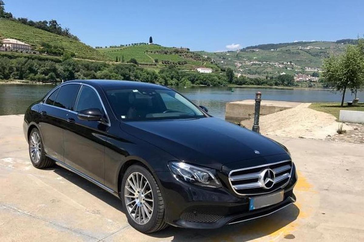 a black car parked in a parking lot next to a river