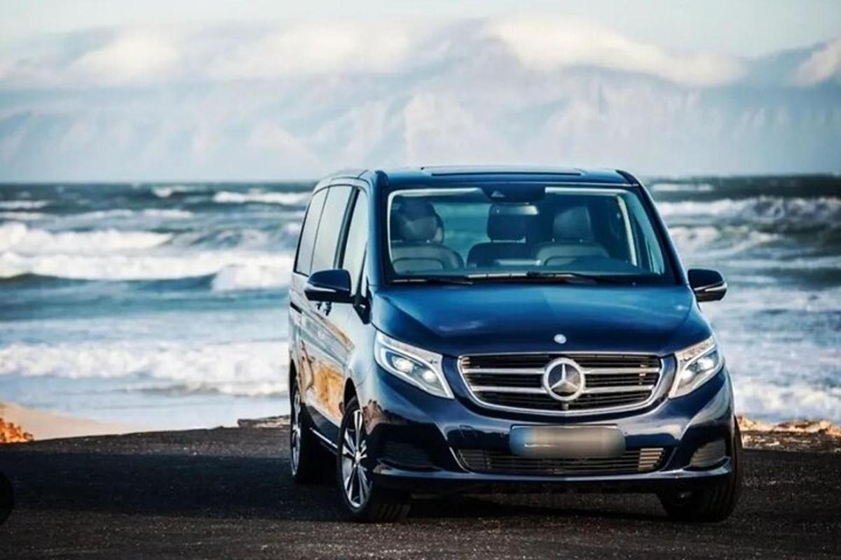 uma van azul estacionada na praia perto do oceano