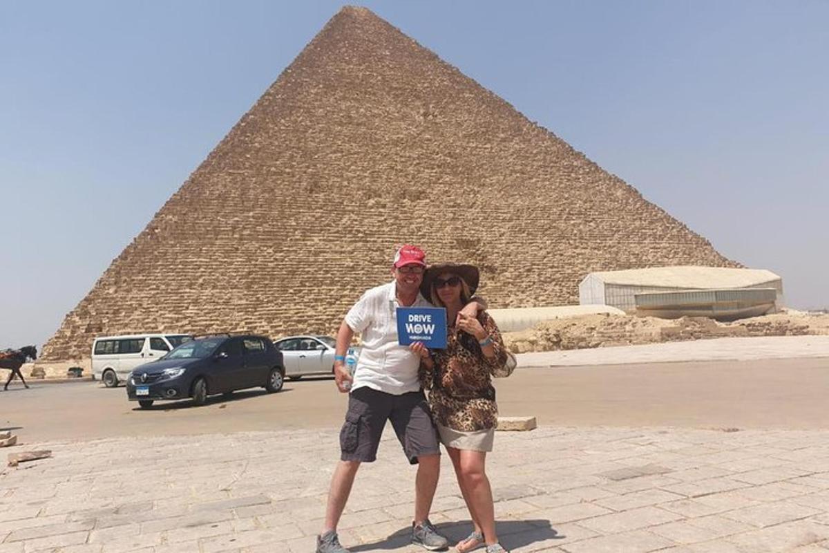 um homem e uma mulher segurando uma placa em frente a uma pirâmide