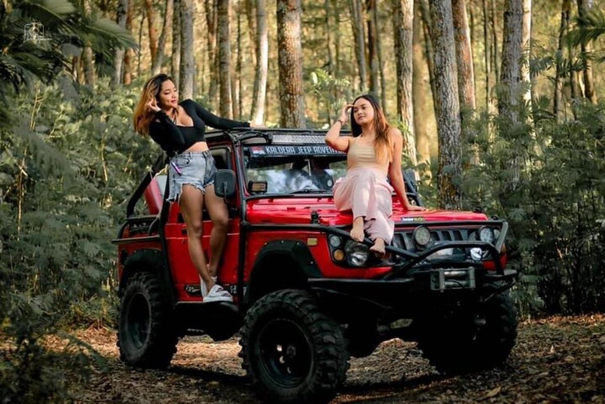 dua wanita duduk di belakang jip merah