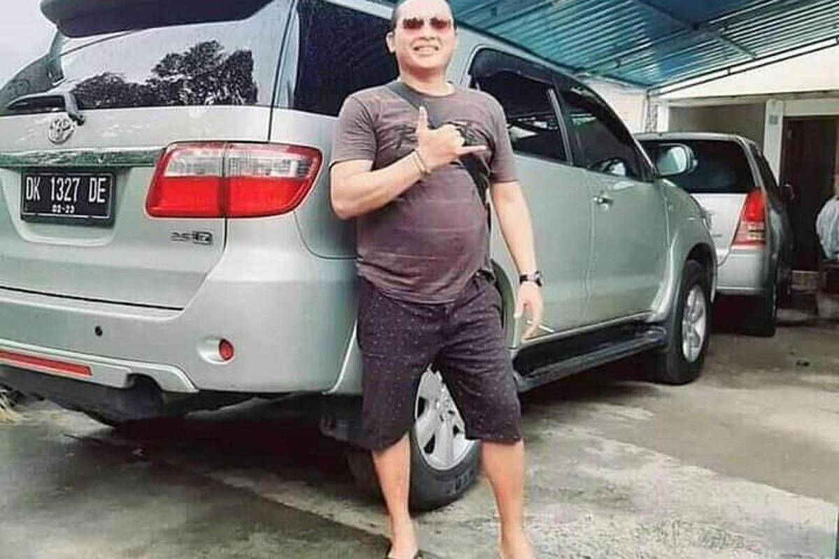một người đàn ông đứng trước một chiếc xe hơi