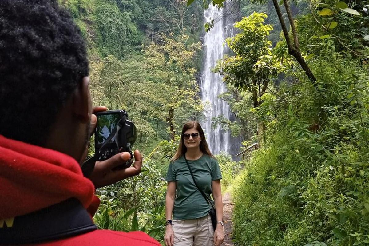 a man taking a picture of a woman in front of a waterfall