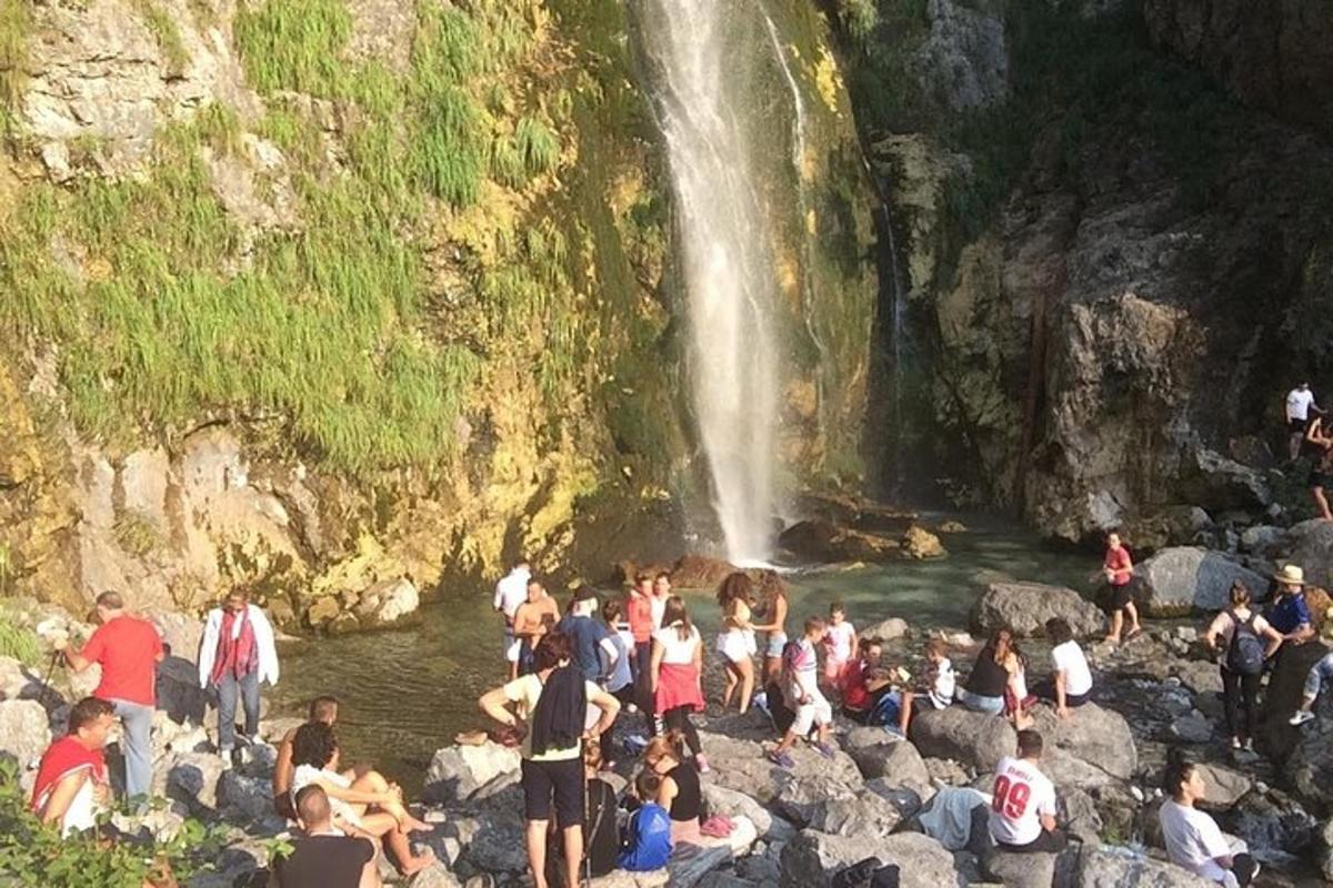 skupina lidí ve vodě poblíž vodopádu