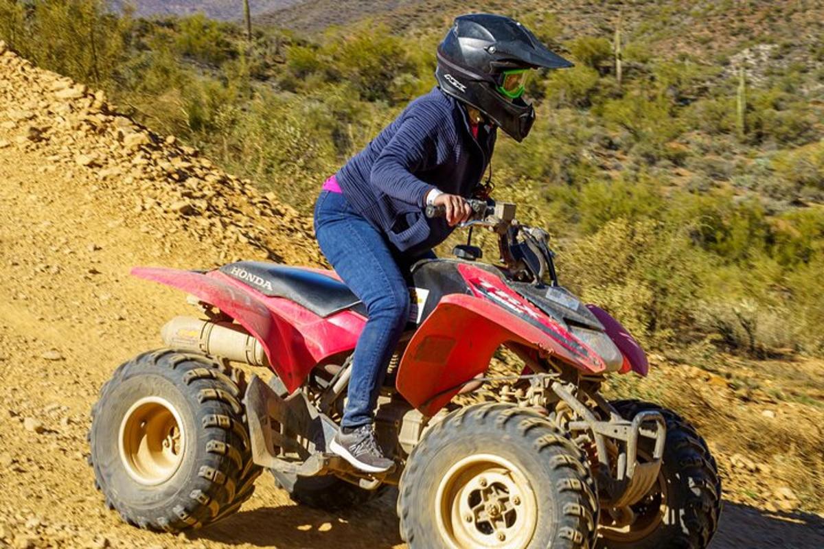 una persona che viaggia su un veicolo a quattro ruote su una strada sterrata