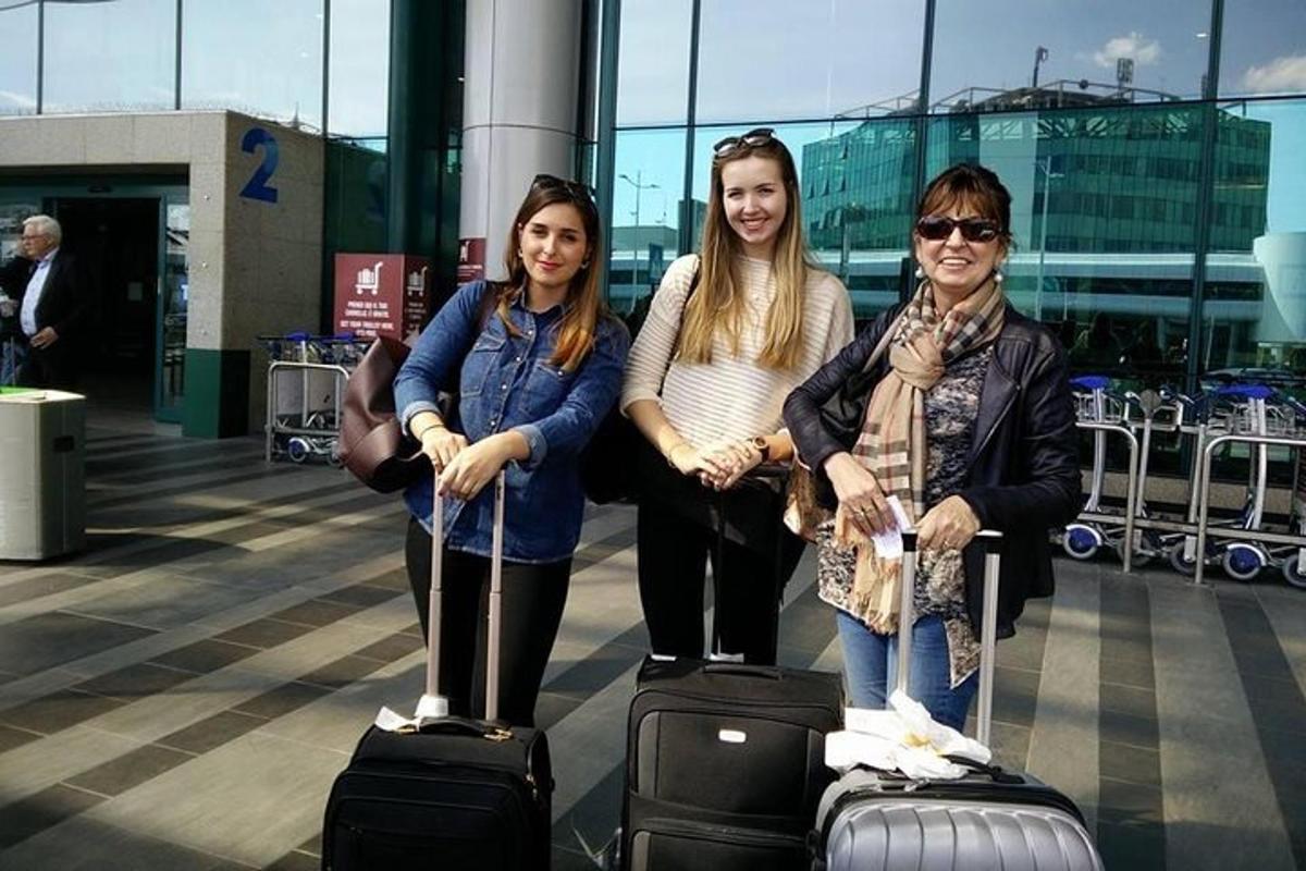 three women posing with their luggage at an airport
