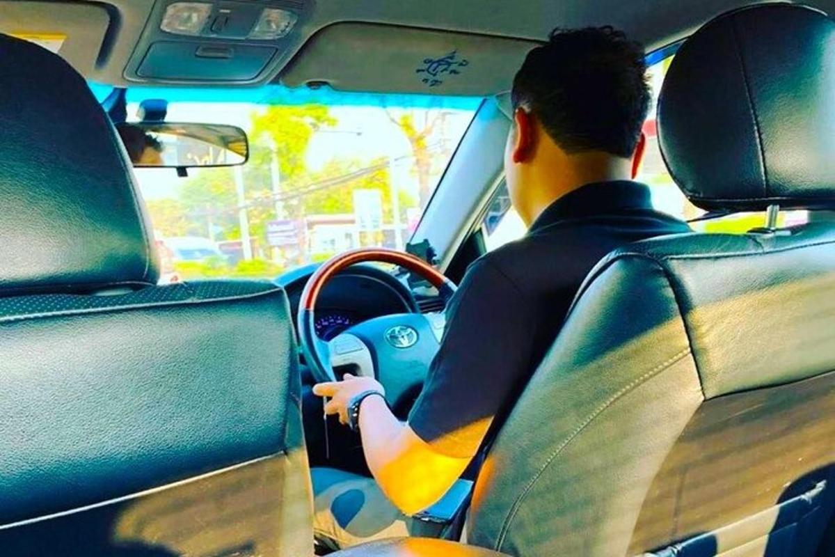 a man driving a car with a surfboard on the dashboard