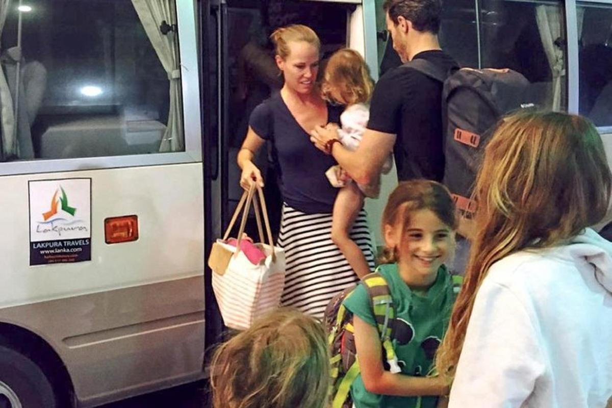 a woman holding a child standing next to a bus