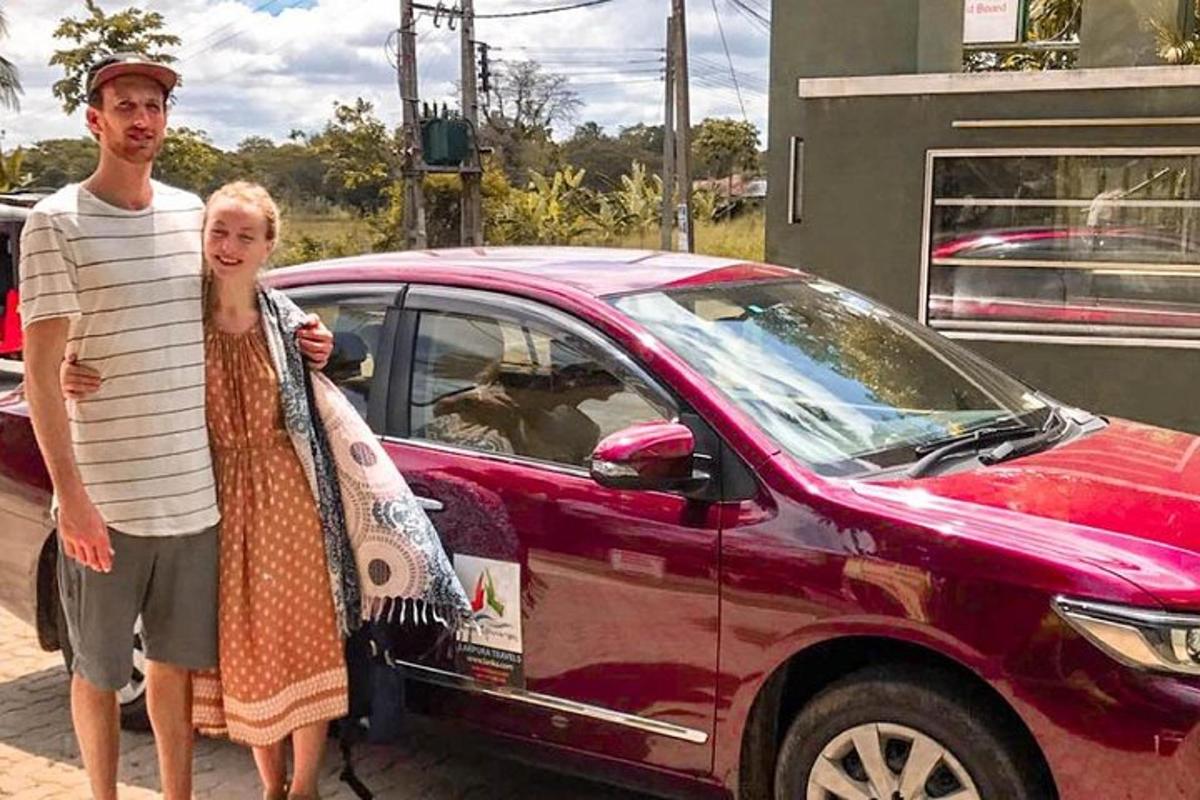 чоловік і жінка стоять поруч із червоним автомобілем