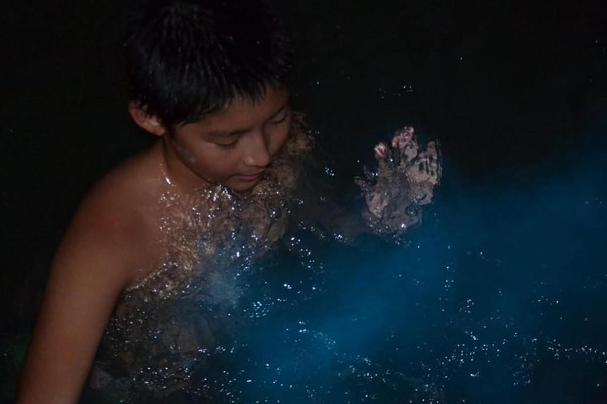 một cậu bé đang ở dưới nước với một con chó