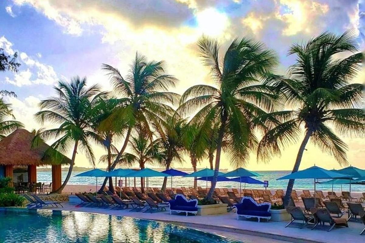 a resort swimming pool with chairs and palm trees