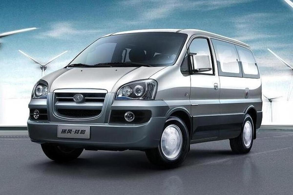 a silver van parked in a parking lot with windmills