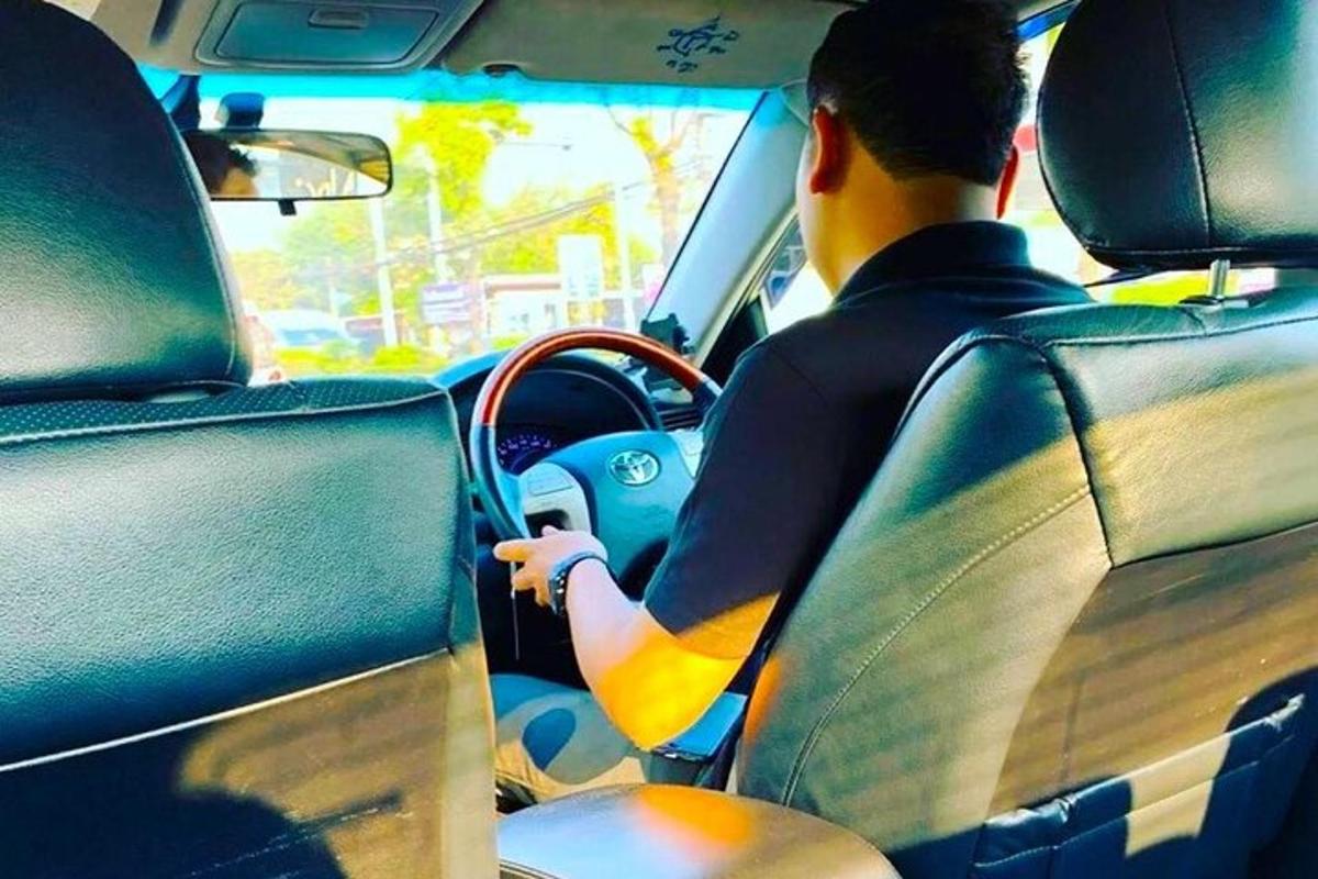 un uomo alla guida di un'auto con una tavola da surf sul cruscotto
