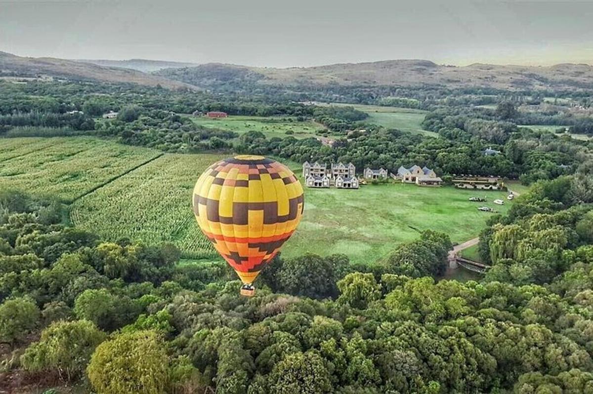 um balão de ar quente amarelo voando sobre um campo