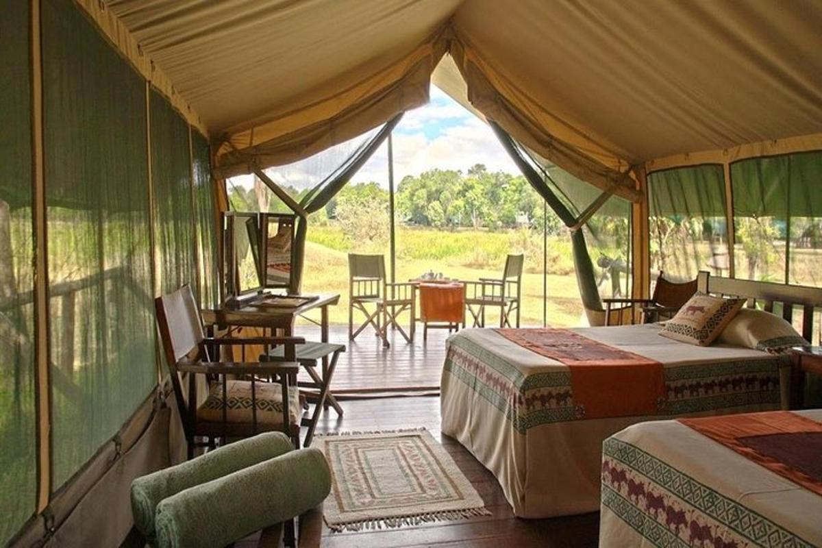 a tent bedroom with two beds and a table and chairs