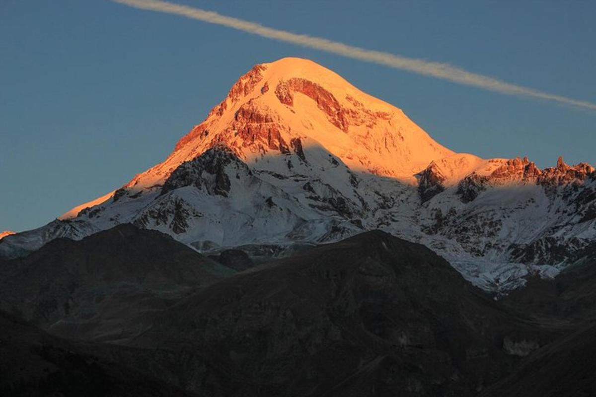 uma montanha coberta de neve com o sol brilhando sobre ela