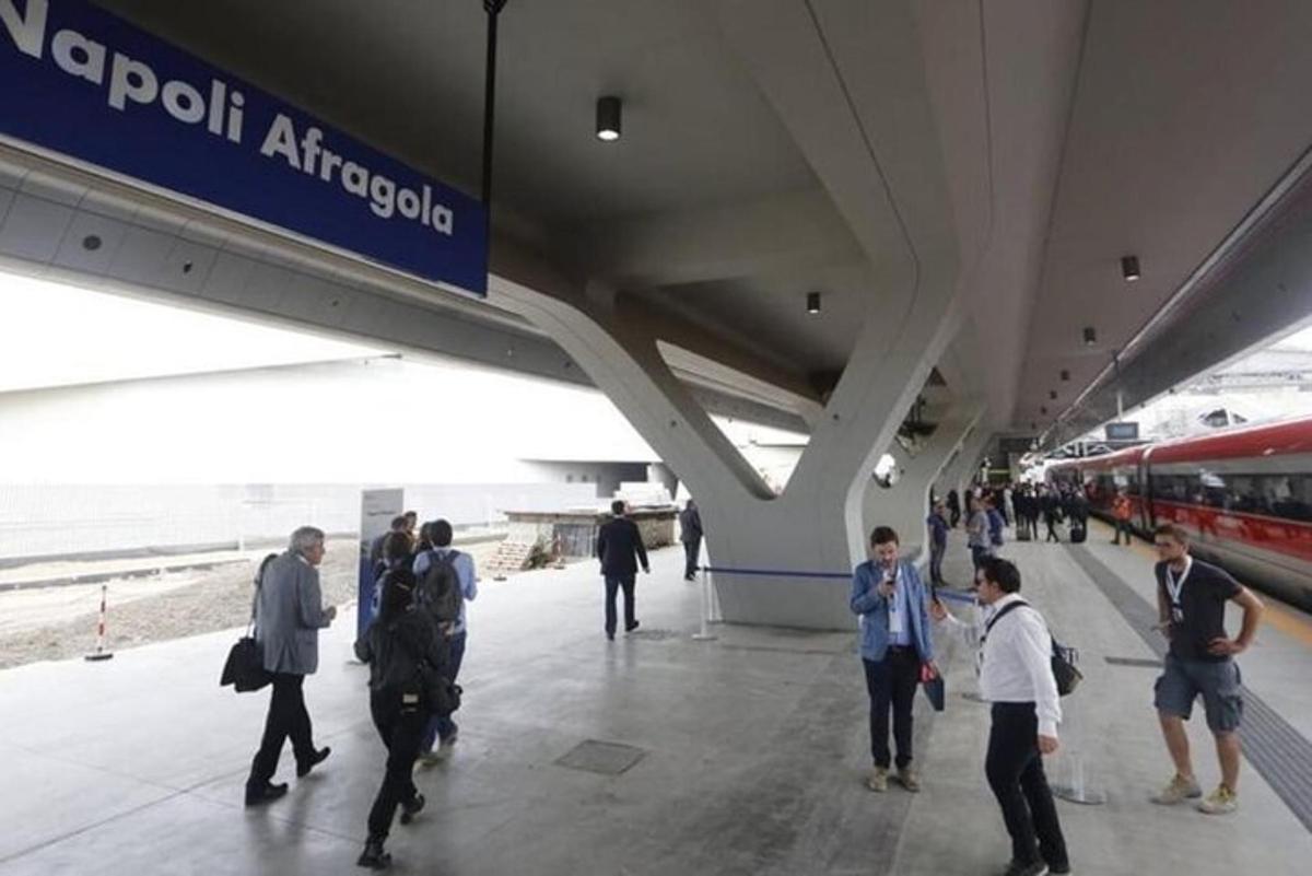 μια ομάδα ανθρώπων που περιμένουν ένα τρένο σε έναν σιδηροδρομικό σταθμό