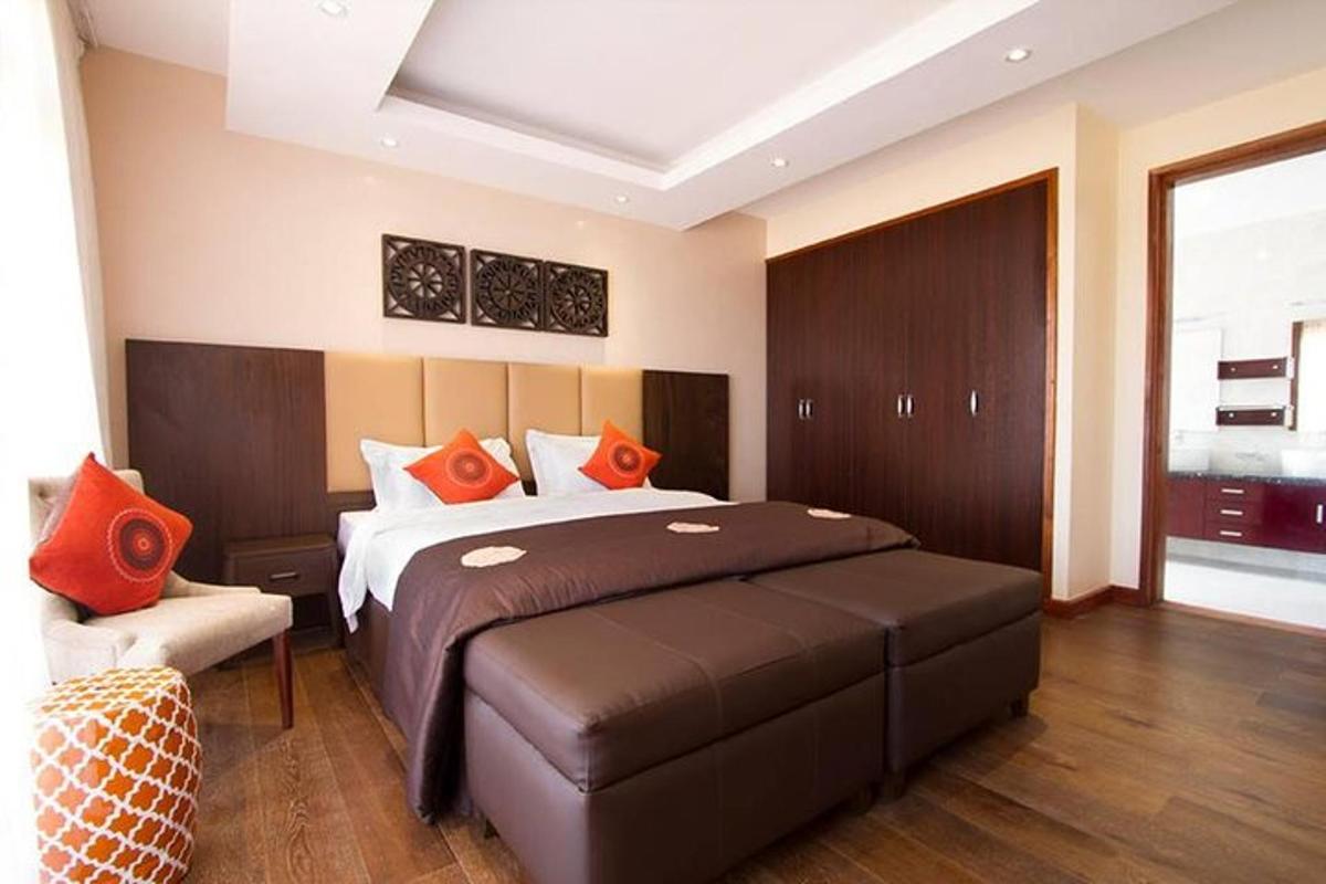 um quarto com uma cama grande com travesseiros laranja