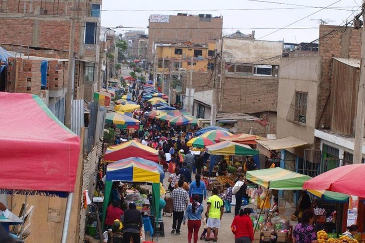 a crowd of people walking through a market with umbrellas