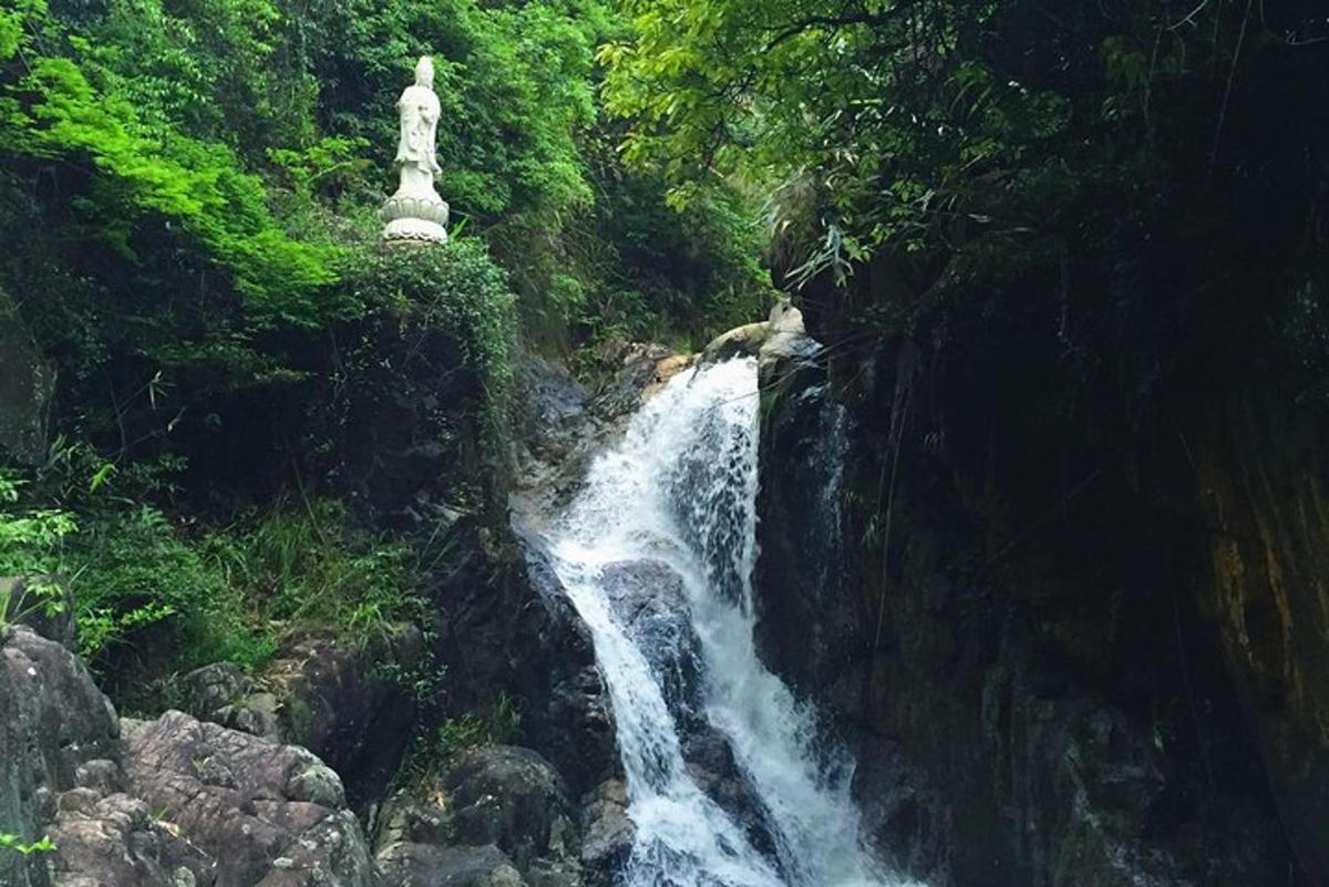 ūdenskritums meža vidū ar statuju