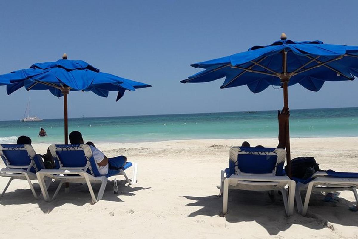tre persone sedute su sedie su una spiaggia con ombrelloni