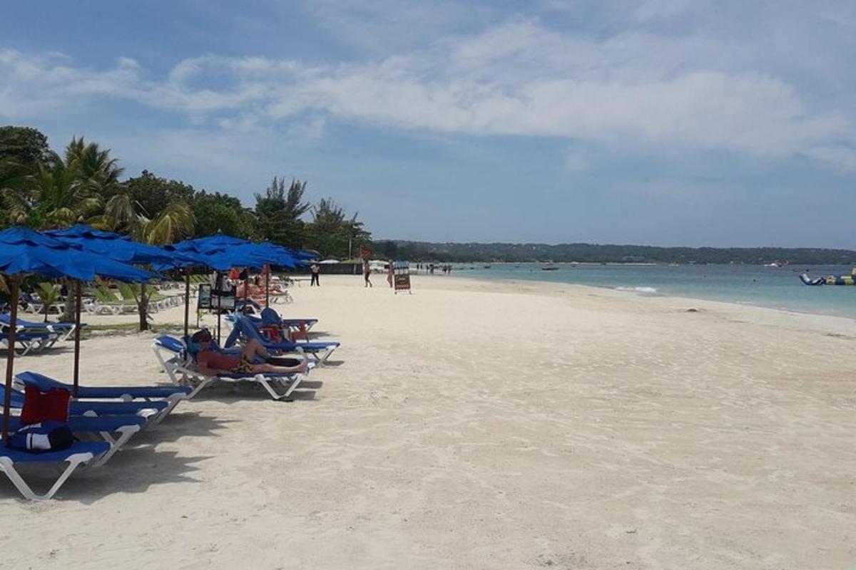 una spiaggia con sedie e ombrelloni blu e l'oceano