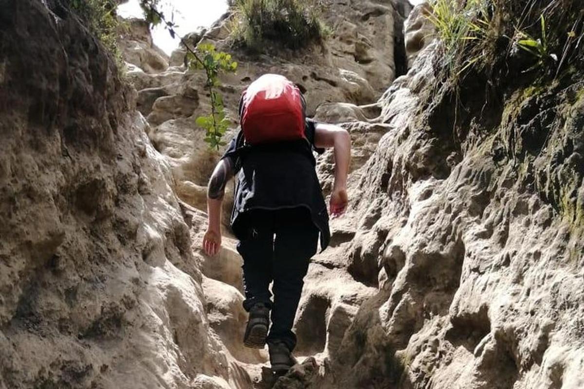 Un hombre con una mochila caminando por un sendero rocoso