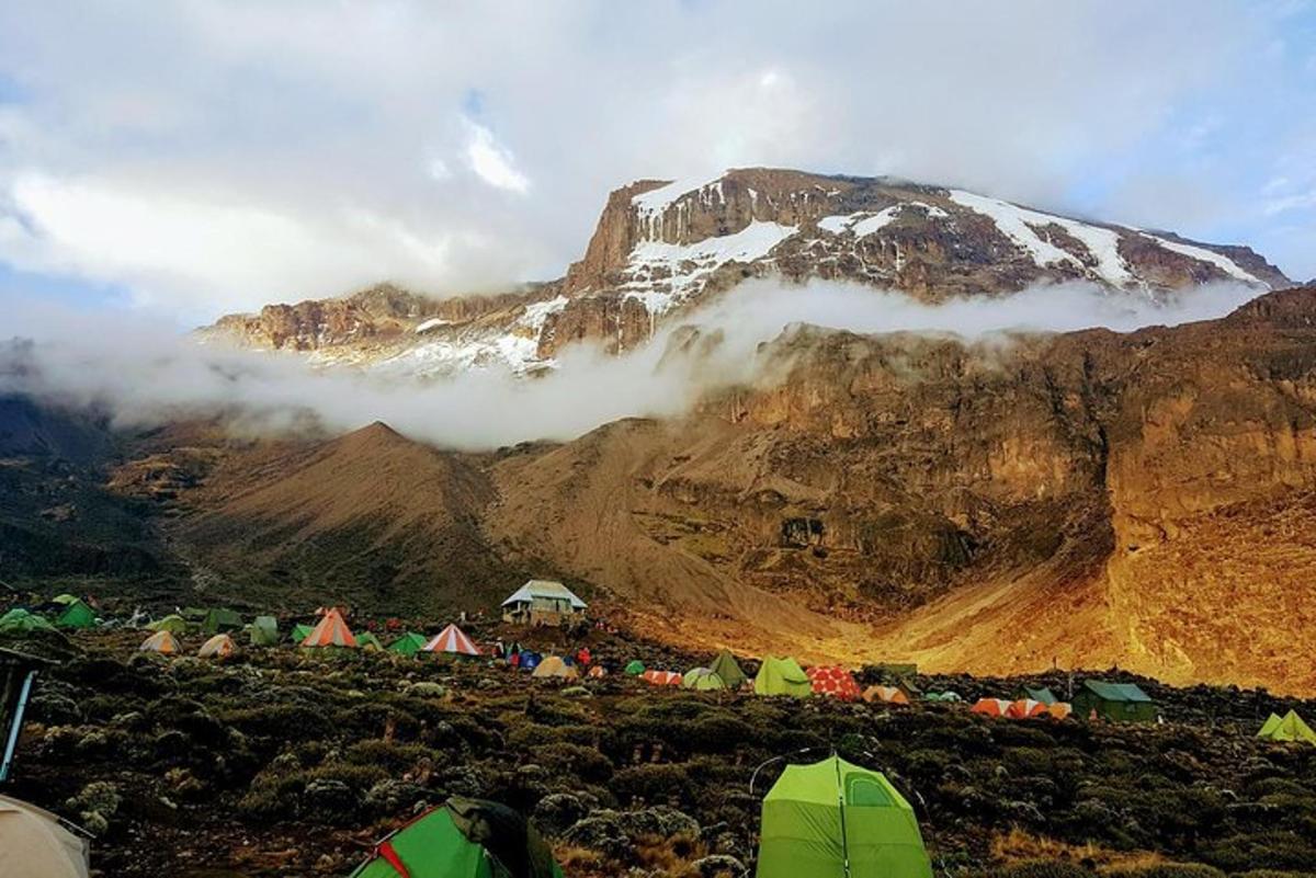 a group of tents on a mountain with a snow covered mountain