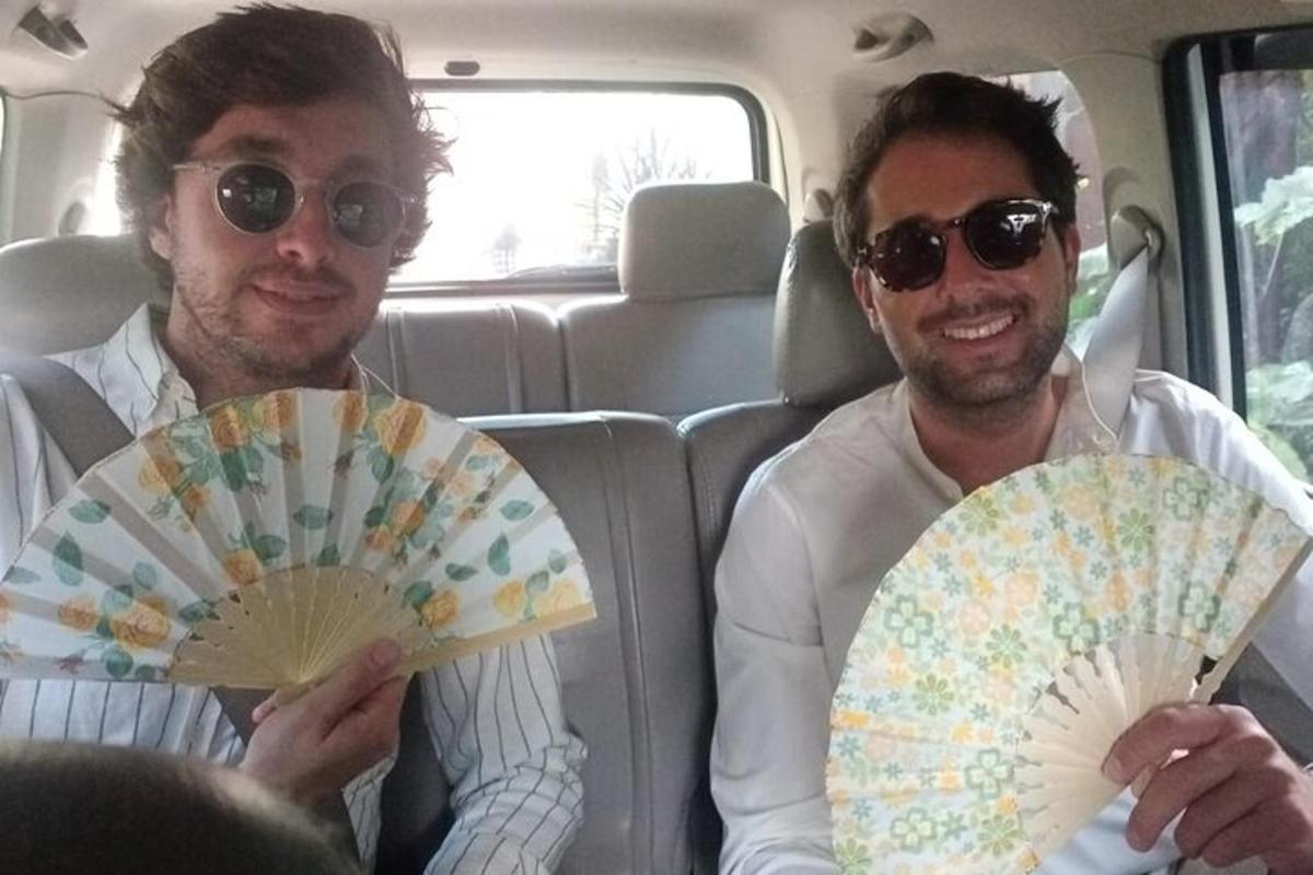 due uomini seduti in macchina che tengono in mano un ventilatore