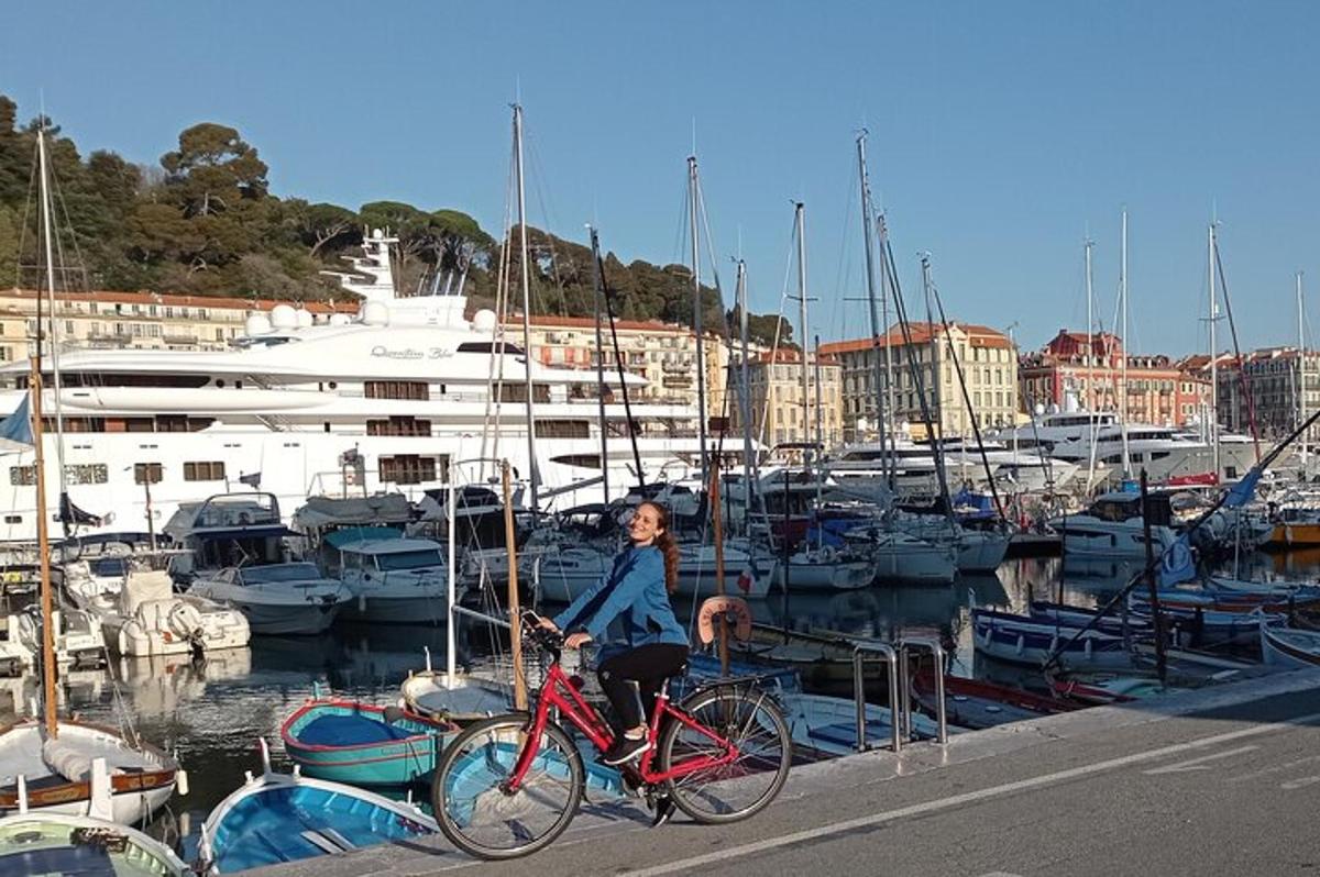 a woman riding a bike at a marina with boats