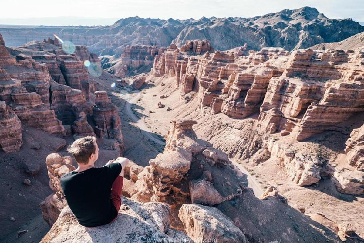 a man sitting on a rock looking at the grand canyon