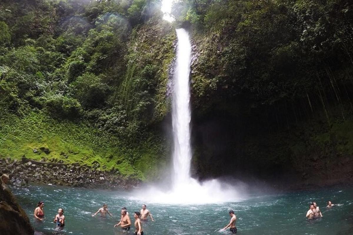 a group of people swimming in the water near a waterfall