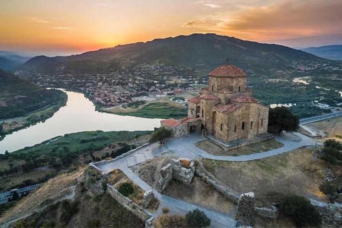 an old building on a hill next to a river