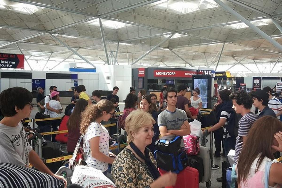 a crowd of people waiting in line at an airport