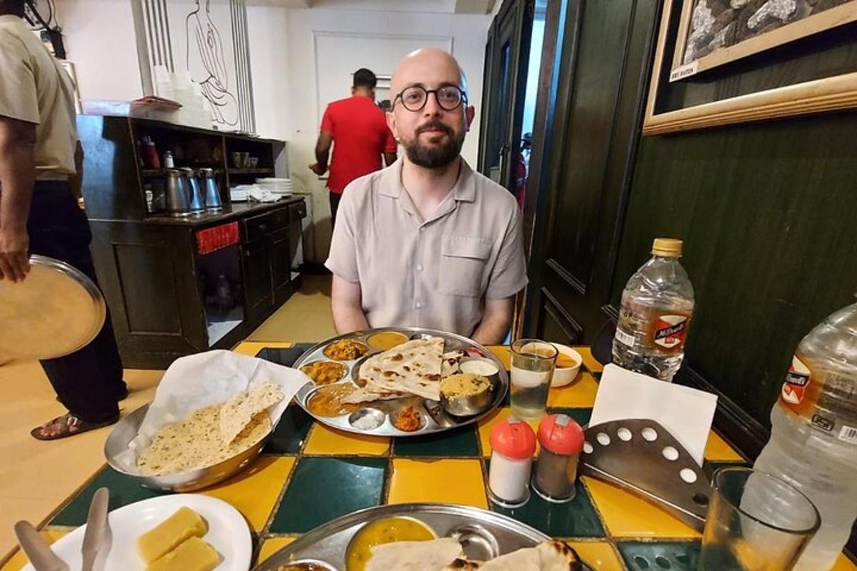 maður situr við borð með disk af mat